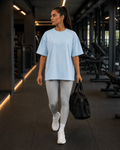 Oversized Tee in Sky Blue, woman walking through a gym with a duffel bag